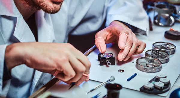 Expirienced clockmaster is fixing old watch for a customer at his repairing workshop