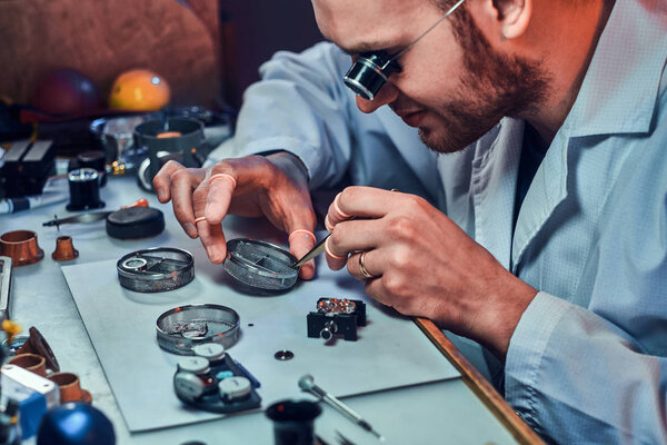 Expirienced clockmaster is fixing old watch for a customer at his repairing workshop