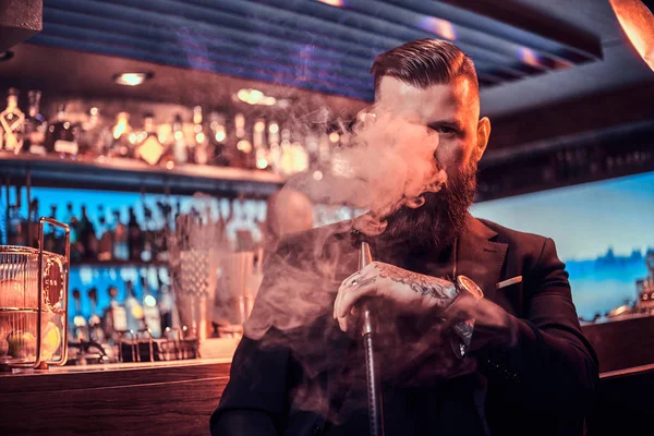 Портрет татуйованого бородатого чоловіка, який курить кальян, роблячи гарний пар — стокове фото