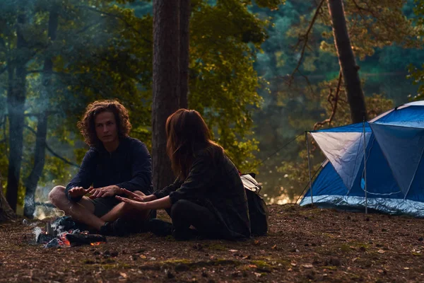 Vonzó romantikus pár bemelegítés közelében tábortűz az esti erdőben — Stock Fotó