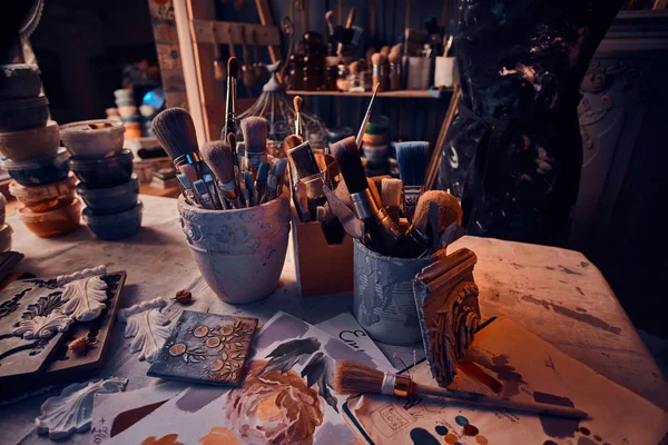 Kavanozlarda sanatçı masasında bir sürü farklı fırça. Masada artistikler var.. — Stok fotoğraf