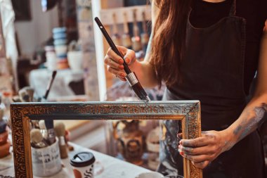 Genç yetenekli ressam eski çerçeveyi kendi atölyesinde yeniden düzenliyor.