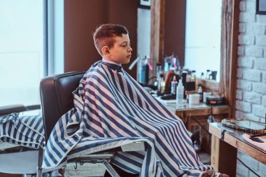 Küçük okul çocuğu modern berber dükkanında ilk moda saç kesimi vardı.
