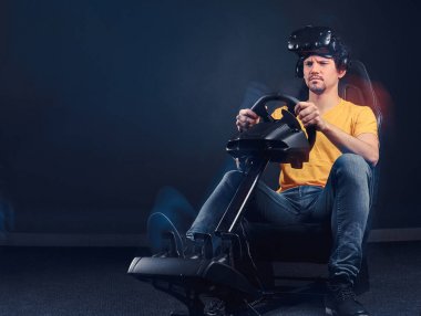 Koltuk ve tekerlek ile araba yarış simülatörü kokpitte sürüş Vr kulaklık giyen adam.