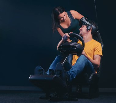 Araba yarış simülatörü otururken kız arkadaşı ile konuşurken adam. Sanal gerçeklik gözlük oyunlar.