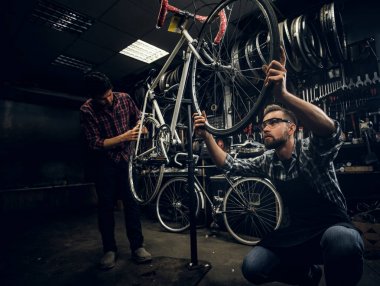 Çekici adam karanlık atölyede bisiklet sabitleme üzerinde çalışıyoruz.