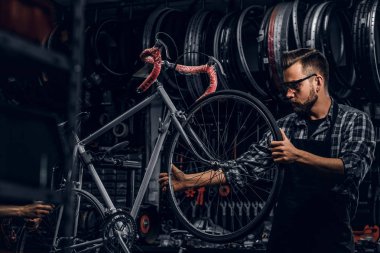 Koruyucu gözlük yakışıklı ciddi adam kendi dükkanında bisiklet tamir