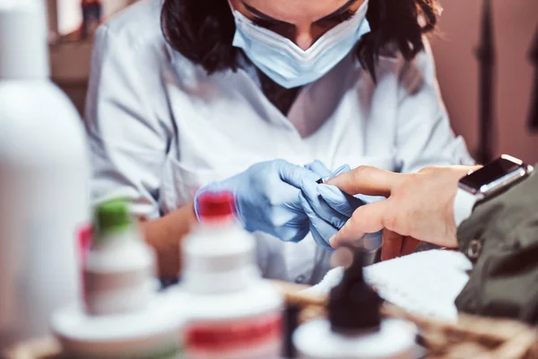 El maestro esteticista hace un procedimiento de manicura. Un hombre recibiendo una manicura en el salón de belleza —  Fotos de Stock