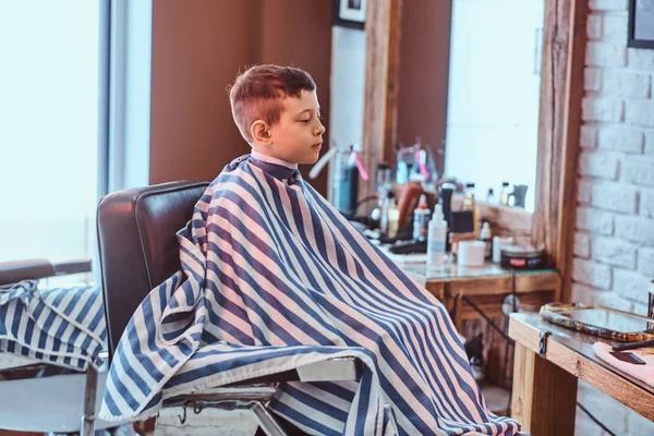 Small school boy had his first trendy haircut at modern barbershop. — Stock Photo, Image