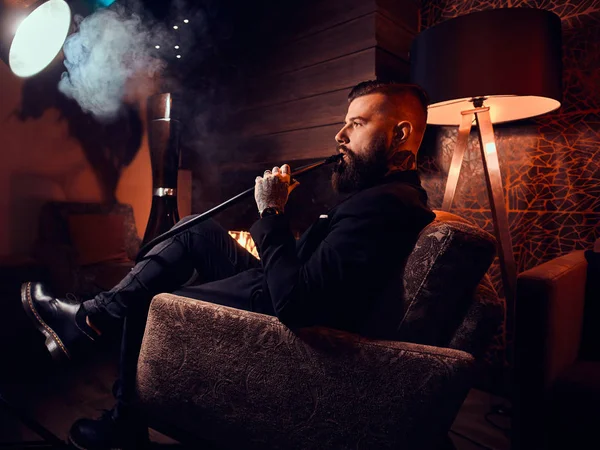 Елегантний розумний чоловік розслабляє і курить кальян після довгого важкого дня — стокове фото