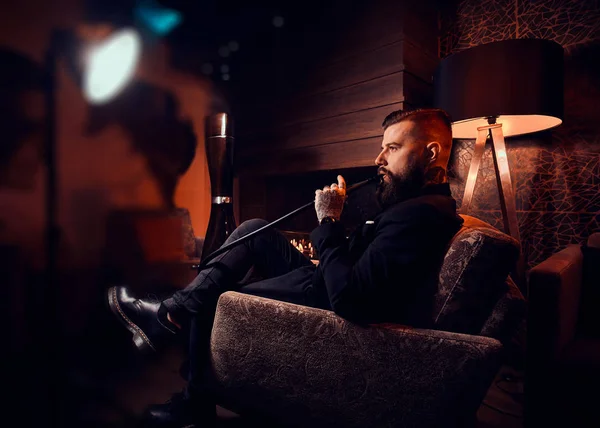Schöner bärtiger Mann entspannt in der Lounge, während er Wasserpfeife raucht — Stockfoto