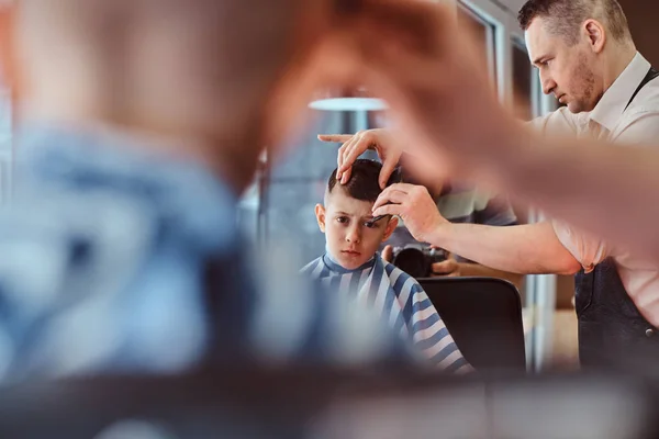 Pequeno menino da escola bonita teve seu primeiro corte de cabelo na moda na barbearia moderna — Fotografia de Stock