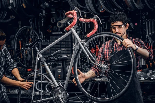 Reparadores de trabajo duro están arreglando la bicicleta en su taller ocupado — Foto de Stock