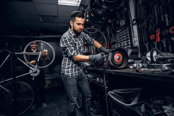 L'homme attrayant travaille avec la machine à l'atelier de vélo occupé . — Photo