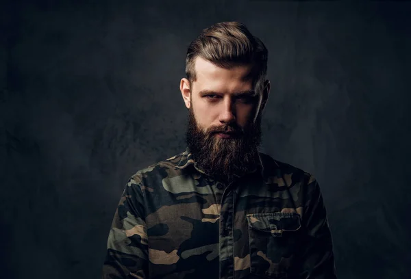 Retrato de un elegante barbudo con manos tatuadas en la camisa militar. Estudio foto contra la pared oscura — Foto de Stock