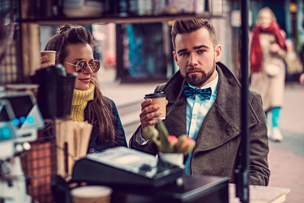 Atraente casal inteligente está desfrutando de café enquanto sentado fora em pequeno café — Fotografia de Stock