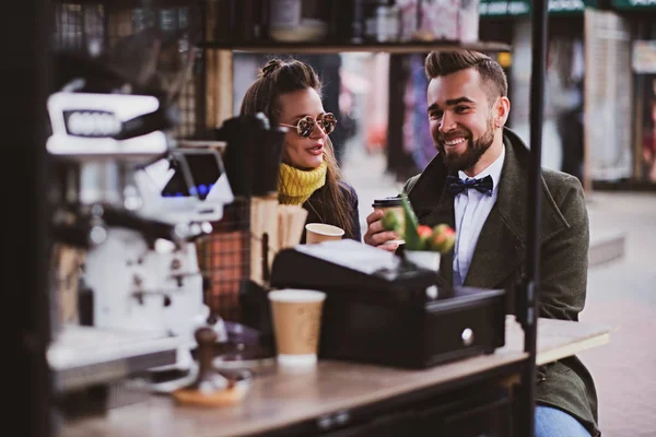 Atraente casal inteligente está desfrutando de café enquanto sentado fora em pequeno café — Fotografia de Stock