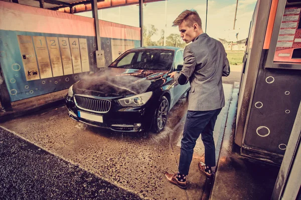 Молодой ухоженный мужчина моет свою машину на автомойке — стоковое фото