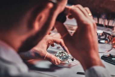 Olgun clockmaster onun meşgul tamir atölyesinde bir müşteri için eski saat sabitleme