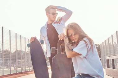 Çekici genç çift onların longboards ile güneşli sokakta rahatlatıcı