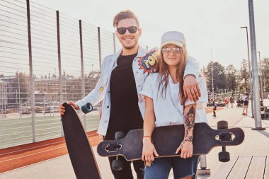 Mutlu gülümseyen çift onların longboards ile yaz sokakta duruyor