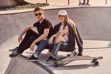 Serin trendy öğrenciler longboards ile güneşli kaykaylar oturuyor