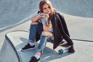 Uzun saçlı trendy kadın onu longboard üzerinde skatepark oturuyor.