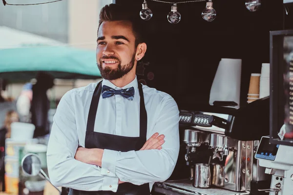 Elegant barista is waiting for customers at his own small coffeeshop.