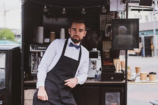 Elegant barista is waiting for customers at his own small coffeeshop.