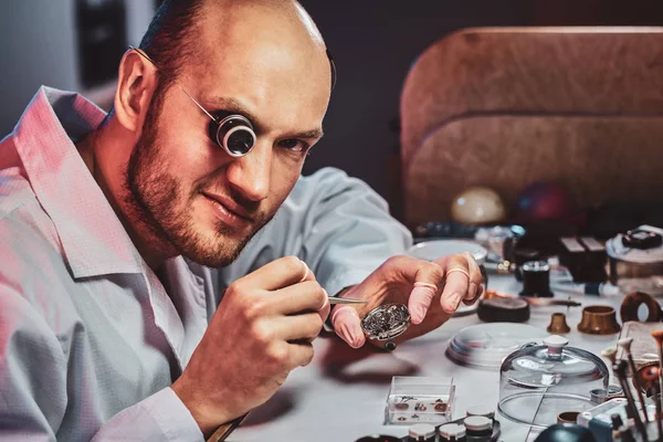 Mature clockmaster is fixing old watch for a customer at his busy repairing workshop — Stock Photo, Image