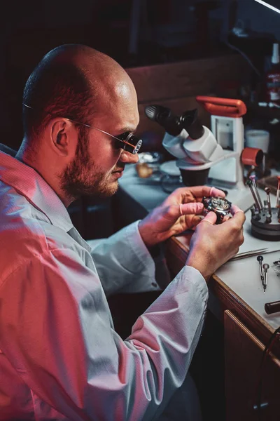 Seriöser Uhrmacher repariert Bestecke in seinem eigenen Reparaturatelier — Stockfoto