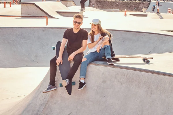 微笑快乐的夫妇坐在溜冰场与他们的长板 — 图库照片