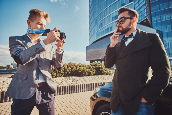Elegante hombre de seguridad está tomando una foto de su jefe, que está fumando mientras está de pie junto a su coche . — Foto de Stock