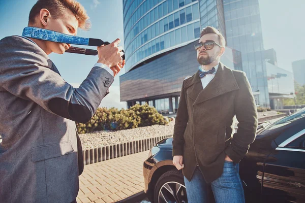 Homem de segurança elegante está tirando fotos de seu chefe, que está ao lado de seu carro . — Fotografia de Stock