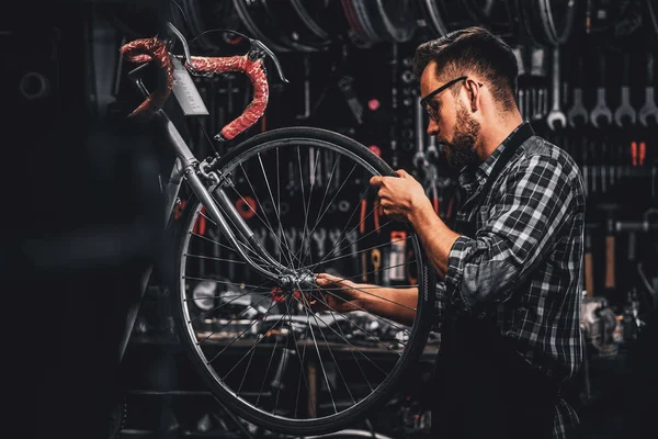 保護眼鏡の魅力的な男性は、彼自身のワークショップで自転車を修理しています — ストック写真