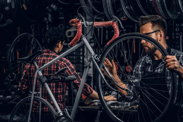 Привлекательный мужчина в очках - цепное колесо для велосипеда в занятой мастерской — стоковое фото
