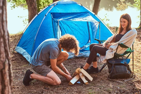 A fiatal utazók egy pár napot a napfényes erdőben sátor közelében — Stock Fotó
