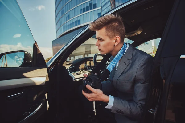 Joven buisnisman está mirando a su teléfono móvil mientras está sentado en el coche . — Foto de Stock