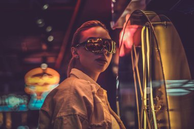 Çekici styilish kadın neon ışıklar fotoğrafçı için poz olduğunu. Arka planda karanlık var..