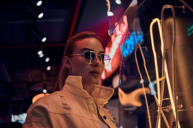 Çekici styilish kadın neon ışıklar fotoğrafçı için poz olduğunu. Arka planda karanlık var..