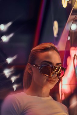 Çekici styilish kadın neon ışıklar fotoğrafçı için poz olduğunu. Arka planda karanlık var..