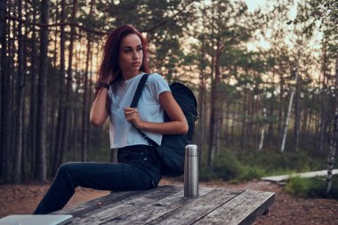 Aktif öğrenci ormanın ortasında masada otururken onun saat üzerinde zaman kontrol ediyor.