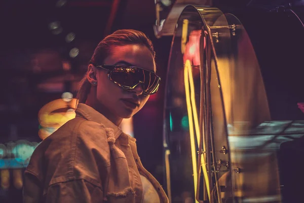 Atrakcyjna kobieta styilish stwarza dla fotografa w neon Lights. W tle są ciemność. — Zdjęcie stockowe