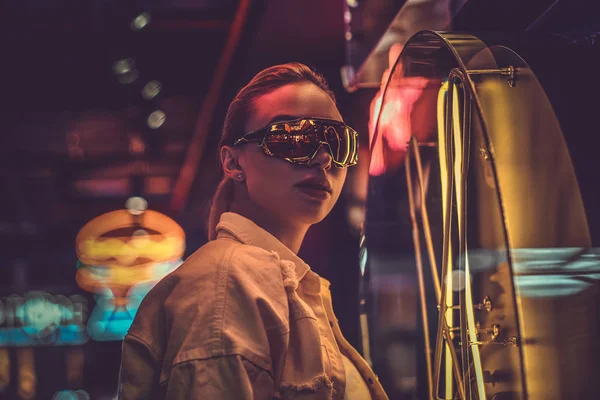 Mujer estilística atractiva está posando para el fotógrafo en luces de neón. Hay oscuridad en el fondo . —  Fotos de Stock