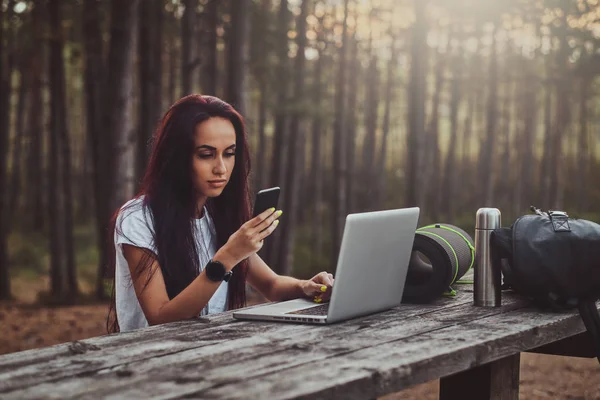 Estudante alegre está trabalhando no laptop no meio da floresta . — Fotografia de Stock