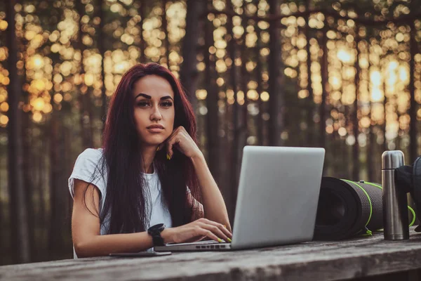 Estudante alegre está trabalhando no laptop no meio da floresta . — Fotografia de Stock