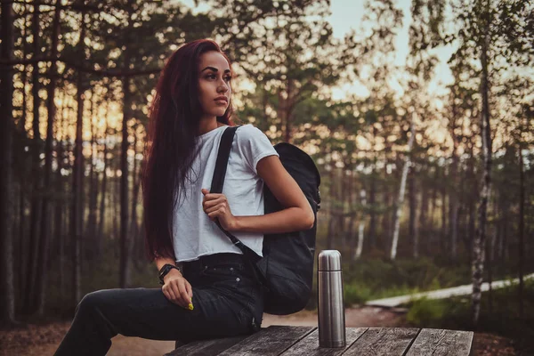 Estudiante activo está descansando después de mucho tiempo hke mientras está sentado en la mesa en el medio del bosque . — Foto de Stock