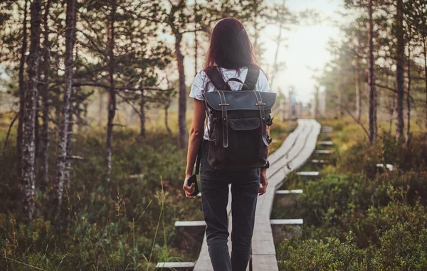 スキニー女性は、緑豊かな松林の真ん中に木製のパスでハイキングしています. — ストック写真