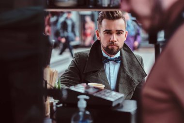 Yakışıklı bakımlı adam kahveteria otururken kahve tadını çıkarıyor