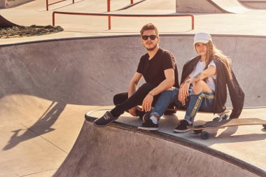 Serin trendy öğrenciler longboards ile güneşli kaykaylar oturuyor